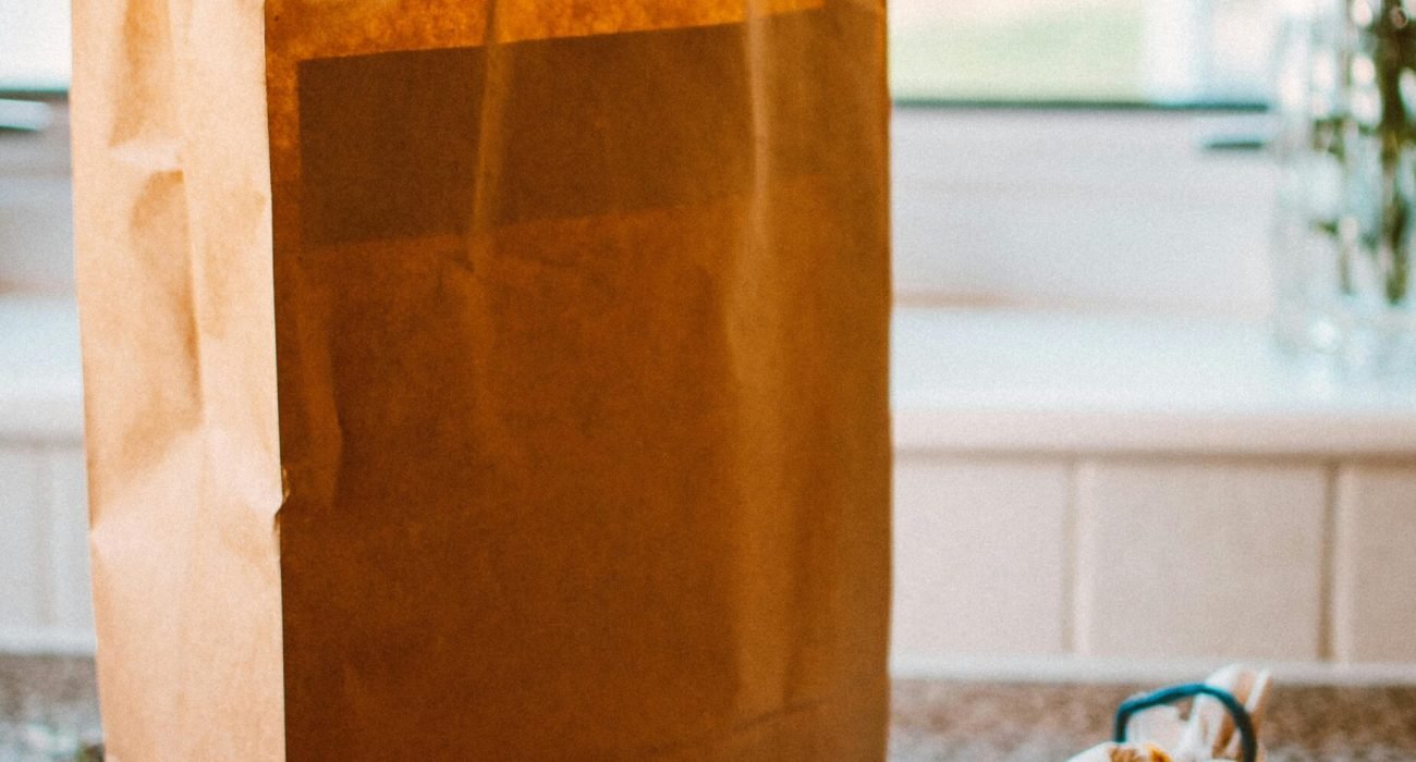 pexels-photo-1992912-1992912 A paper bag with apples and packaged goods on a kitchen countertop, lit by natural light.